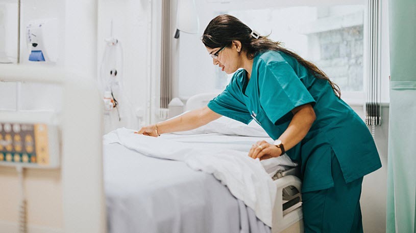Nurse making bed in hospital room