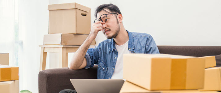 Young Asian man on couch with boxes and laptop