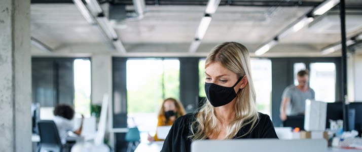 Women in the Workforce A young woman with a face mask works in an office
