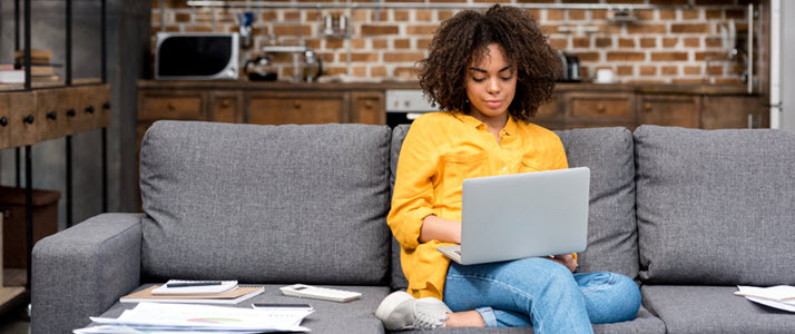 African American woman working on laptop on sofa