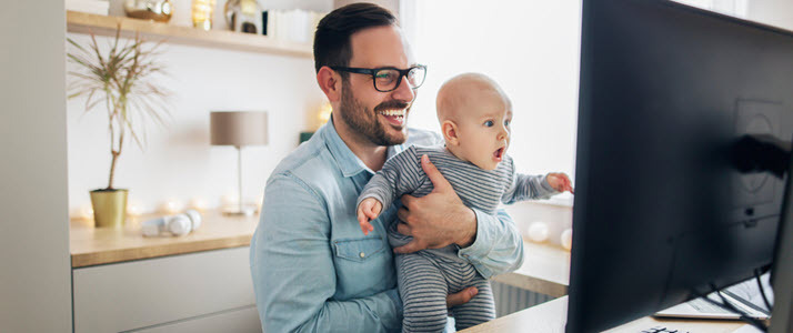 Young smiling father with baby working in home office