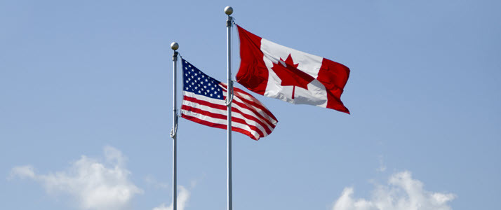 US and Canadian flags flying in the breeze Addressing the Challenges of Managing Employees in Both the US and Canada