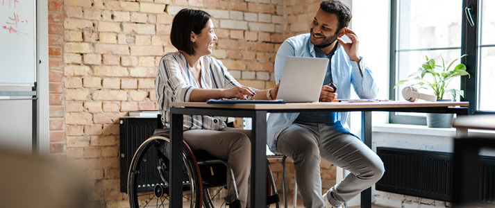 Inclusion in the Workplace Woman in wheelchair working beside man sitting in chair at office