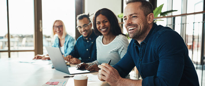 diverse team smiling at conference table How Diverse Equitable and Inclusive Teams Drive Greater Business Value