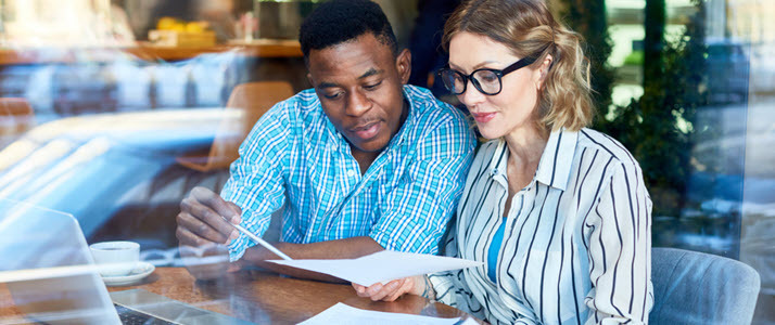 a man and woman at their table at home looking at their financial information