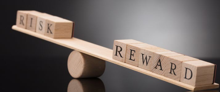 Close up of wooden see saw with words risk and reward Close up of wooden see saw with words risk and reward