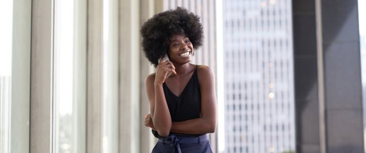 How to Build a Diverse Workforce by Engaging Younger Generations A young Black woman talks on phone in office hallway discussing how to build a diverse workforce