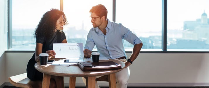 man and woman discussing HR compliance over coffee in office man and woman discussing HR compliance over coffee in office