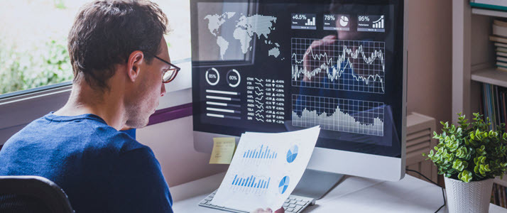 How People Analytics Can Save You Money White man at home office desk reviewing charts and metrics