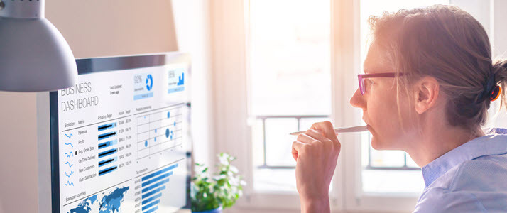 A woman sits at desk looking at people analytics on a computer