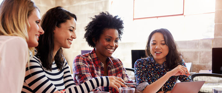 9 Insights on Leading Meaningful Change at Work Four women sit in an office around a laptop looking at the screen