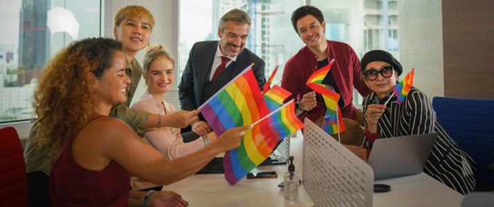 multi-racial group of workers in conference room with PRIDE flag