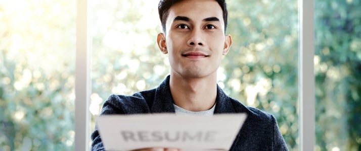 Hiring for Jobs That Require a Degree Young man handing over resume document to interviewer across desk