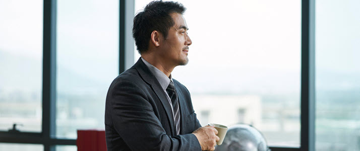 Asian male executive with coffee cup pondering leadership Leadership Interrupted: Welcoming Possibility