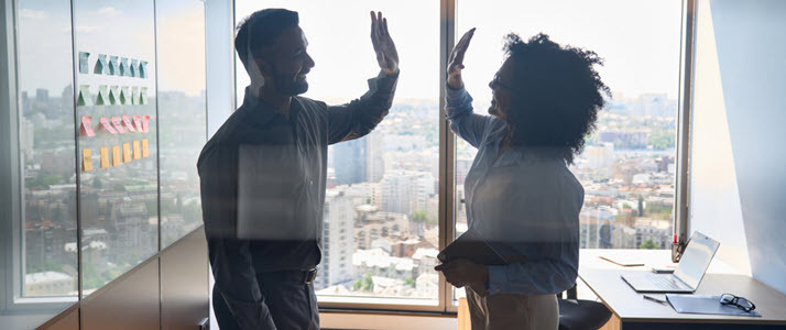 It takes two to deliver meaningful performance improvement two business partners high fiving hands across in conference room