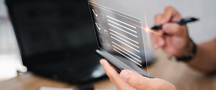 image of hand with pen showing virtual checklist and computer