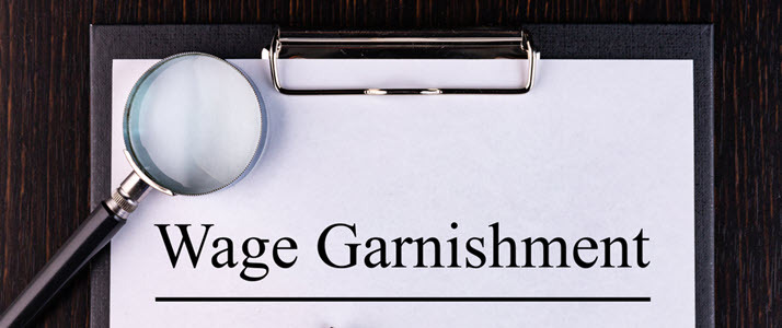 Wage garnishment An employer hands an employee a paycheck with garnished wages