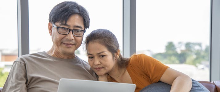 Asian couple at home making decision using laptop
