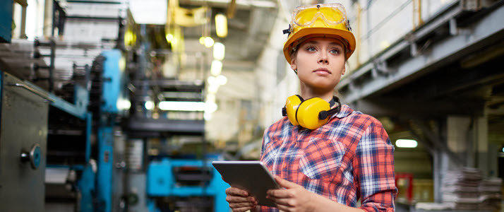 female worker in factory wearing hardhat looking at tablet