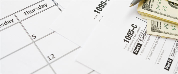 Calendar pages and IRS Form 1095C and currency on table with pen Calendar pages and IRS Form 1095C and currency on table with pen