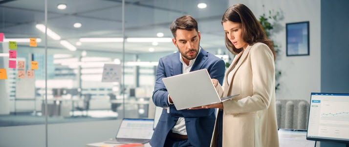 male and female colleagues looking at report on laptop