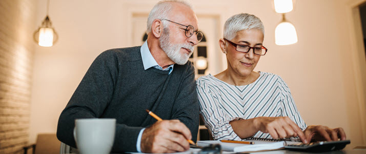 mature couple doing paperwork and using a calculator mature couple doing paperwork and using a calculator