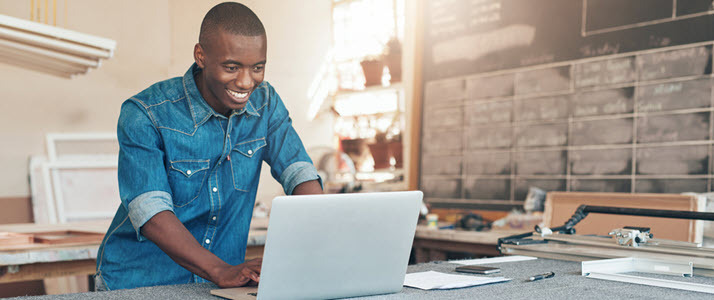small business owner Black man in workshop smiling looking at PC small business owner Black man in workshop smiling looking at PC