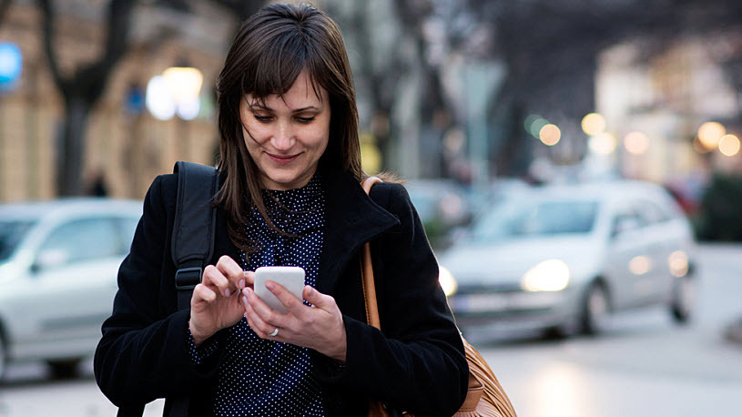 Decorative image - a woman uses smartphone to complete HR tasks