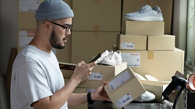 Young businessman packaging sneakers for shipping