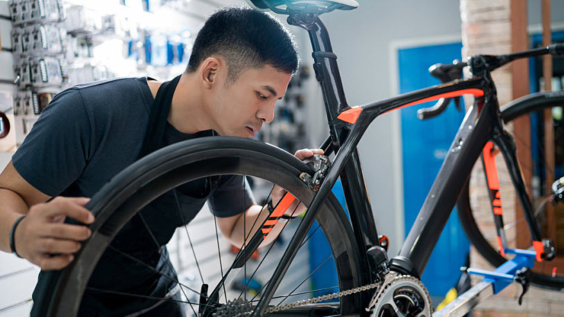 decorative image - young man works on bicycle in repair shop