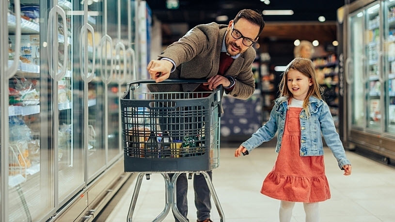Father and daughter at the grocery store choosing frozen food