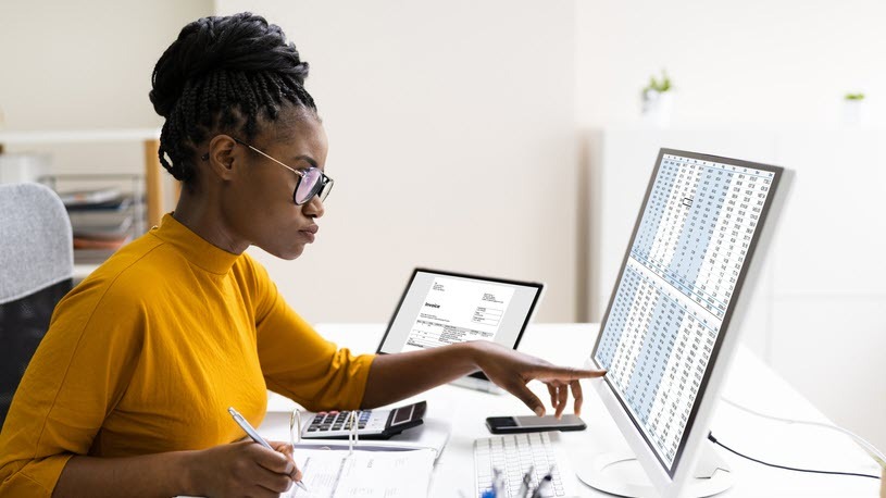 Woman accountant at desktop Woman works with calculator and paperwork at a desktop