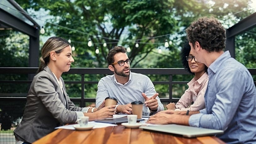 employee engagement tips for summer coworkers meeting outside around a table