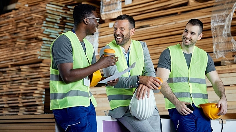 happy coworkers taking coffee break at lumber yard warehouse