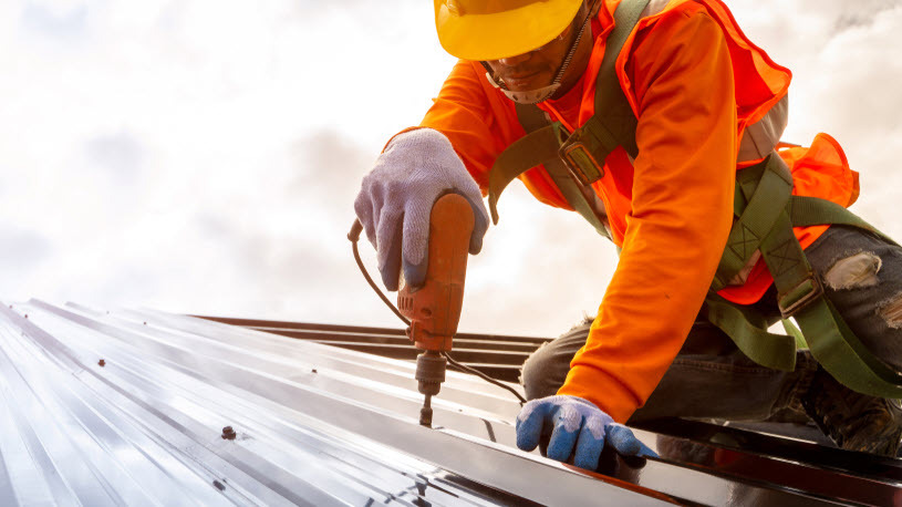 Construction worker on ladder installing roofing Construction worker on ladder installing roofing