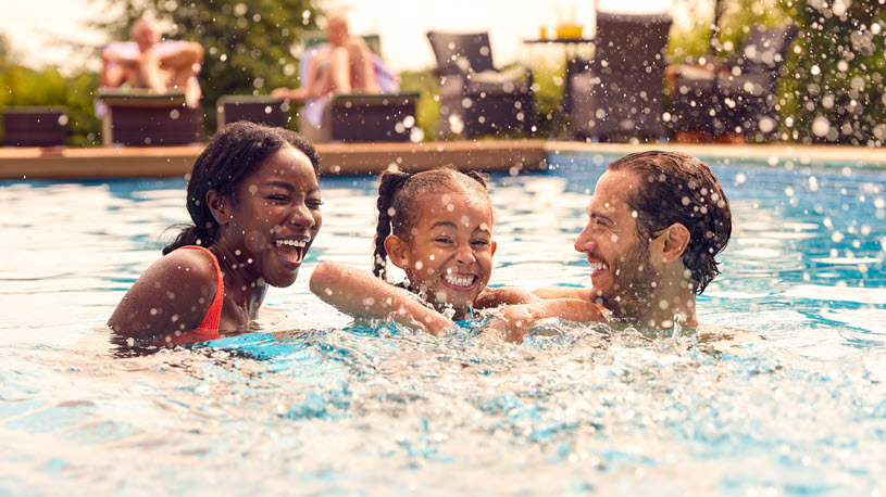 Smiling mixed race parents and daughter laughing in swimming pool