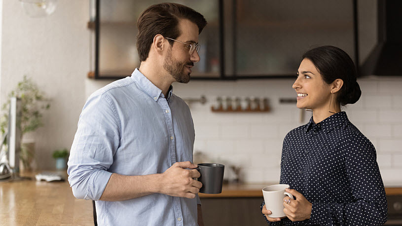 Implementing Pay Transparency Two colleagues together at an office breakroom holding coffee cups.