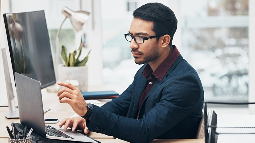 young man working at desk with laptop and keyboard young man working at desk with laptop and keyboard