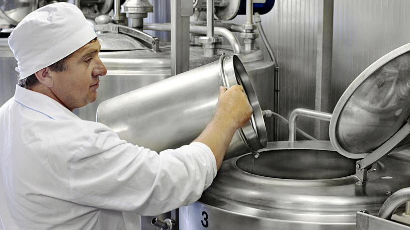 Male dairy manufacturing employee working with storage tanks Male dairy manufacturing employee working with storage tanks