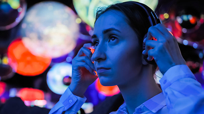Young woman wearing headphones experiences immersive art