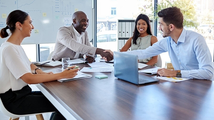 Group of diverse professionals shaking hands at conference table Group of diverse professionals shaking hands at conference table