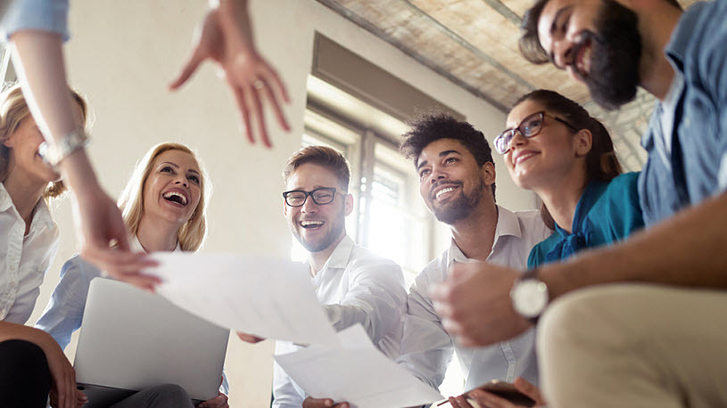 How to Measure Employee Engagement A group of employees in an office setting smiling in a training session.