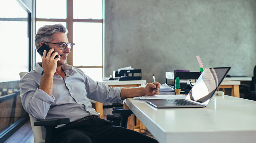 middle-aged male business owner on phone in office with computer