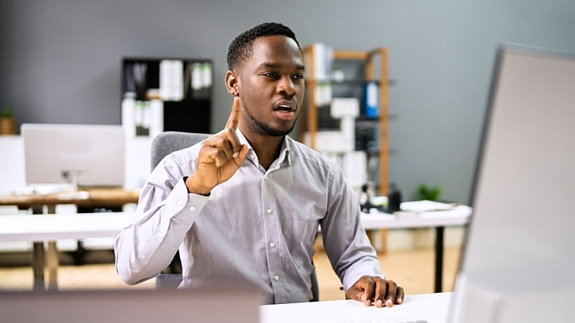 Young Black man at desk interacting on webcast asking a question Young Black man at desk interacting on webcast asking a question