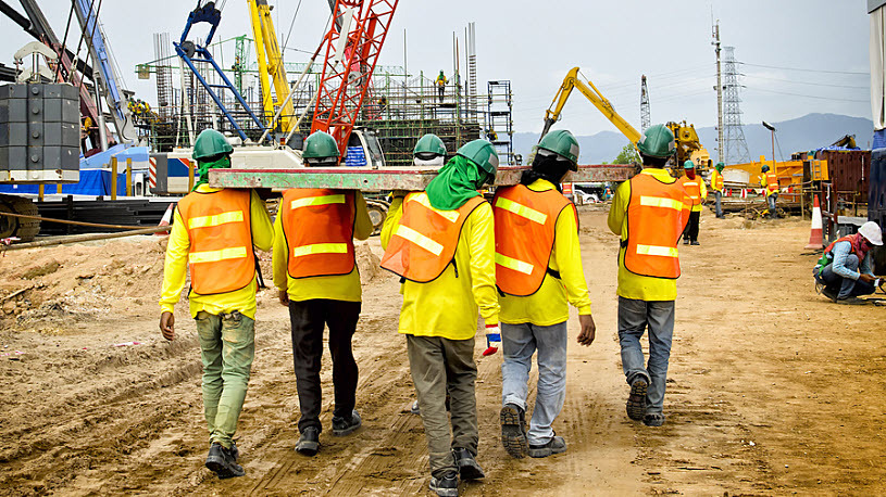 group of construction workers carrying heavy panel at worksite group of construction workers carrying heavy panel at worksite