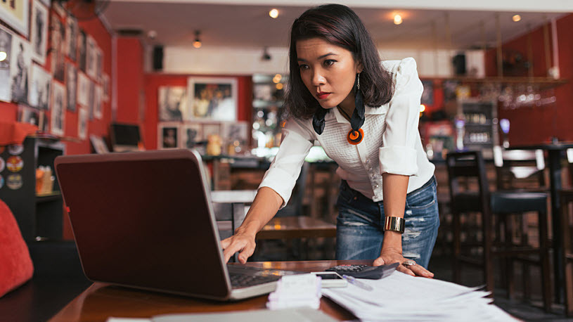 Year-end tax planning A business owner talks reviews taxes and reporting on laptop in her restaurant