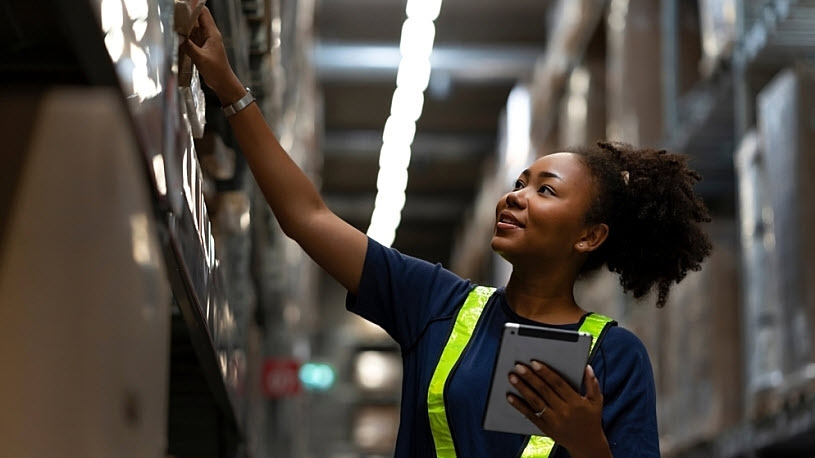 Young Black female smiling with device checking warehouse stock Young Black female smiling with device checking warehouse stock