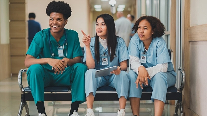 three young hospital employees sitting on a bench chatting