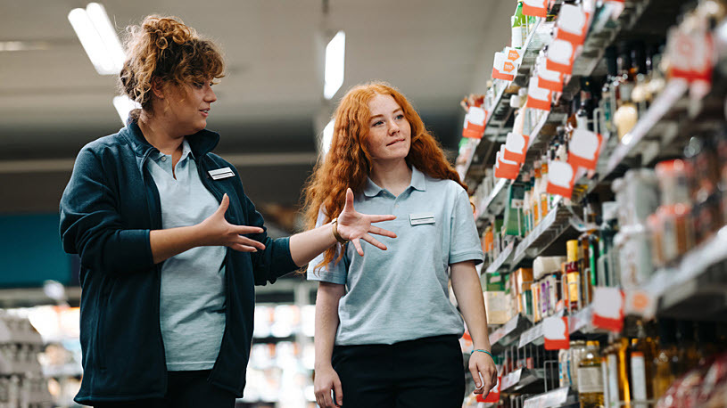 Grocery store manager training new worker in aisle