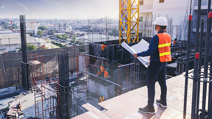 Civil engineer atop skyscraper construction site looking at plans Civil engineer atop skyscraper construction site looking at plans